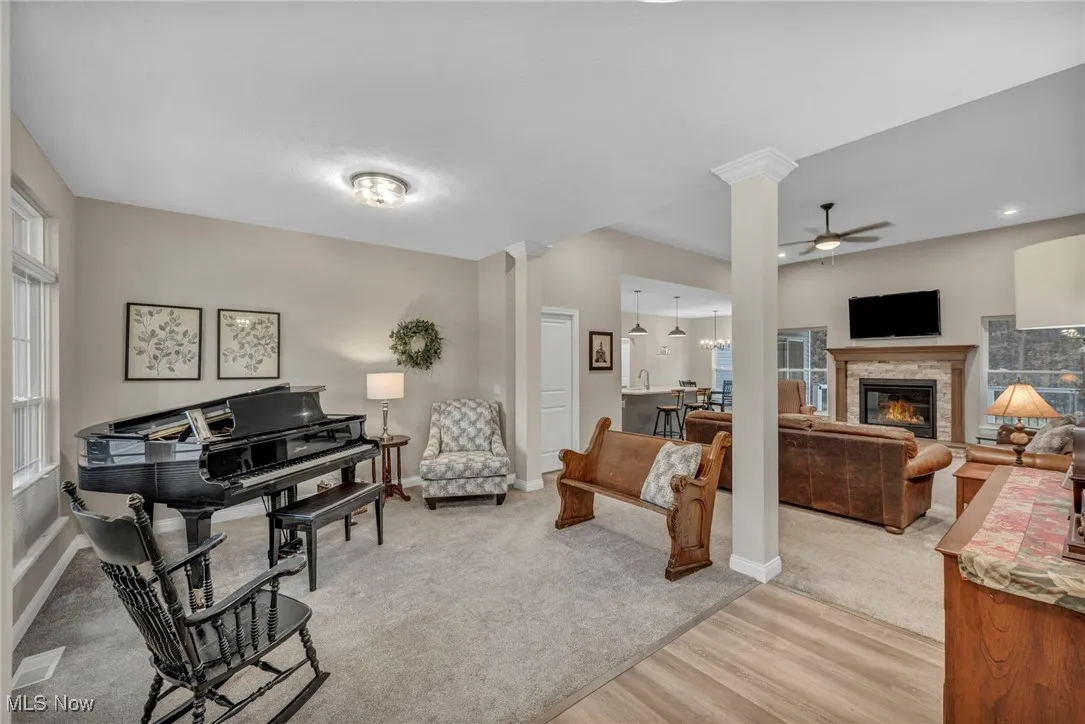 Living area featuring ceiling fan, a glass covered fireplace, light wood-style floors, and light carpet