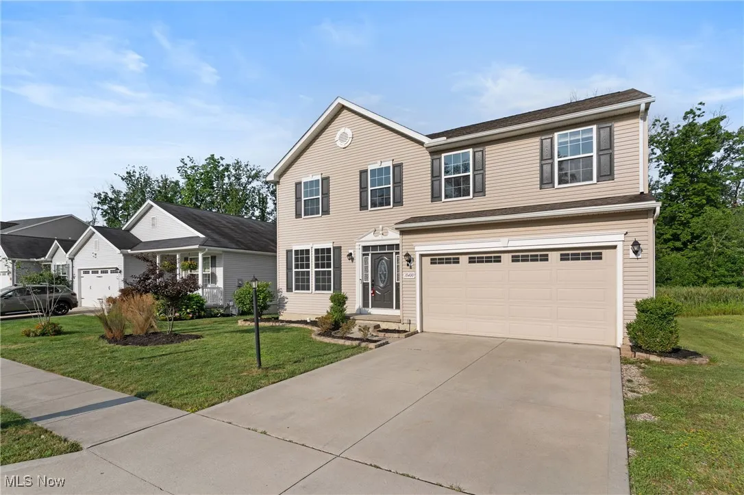View of front facade with driveway, an attached garage, and a front lawn