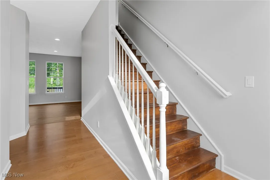 Stairs with wood finished floors and recessed lighting