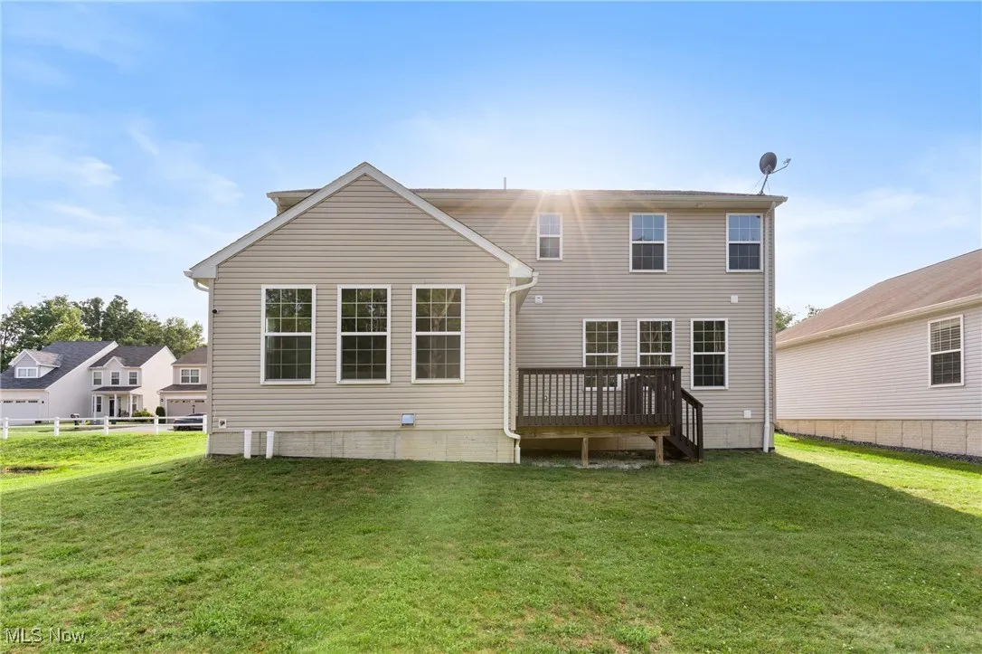 Back of property featuring a deck and a yard