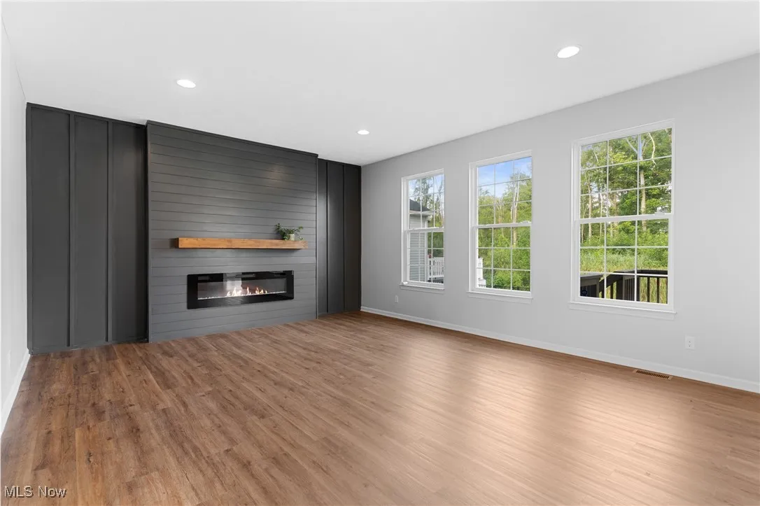 Unfurnished living room featuring a large fireplace, light wood-style flooring, and recessed lighting