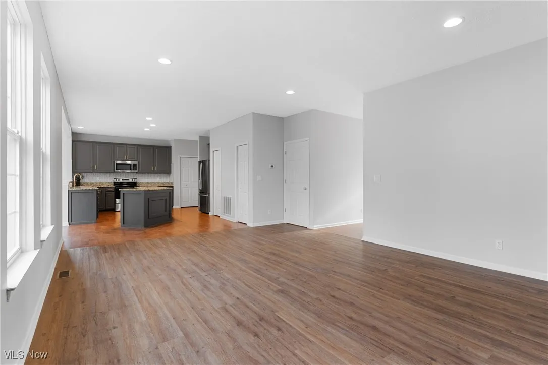 Unfurnished living room featuring dark wood-type flooring and recessed lighting