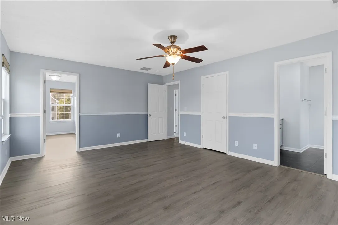Unfurnished bedroom featuring dark wood finished floors, connected bathroom, and ceiling fan