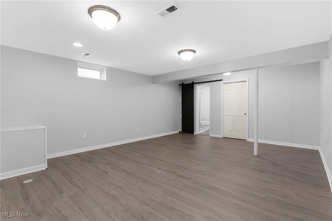 Basement featuring a barn door, light wood finished floors, and recessed lighting