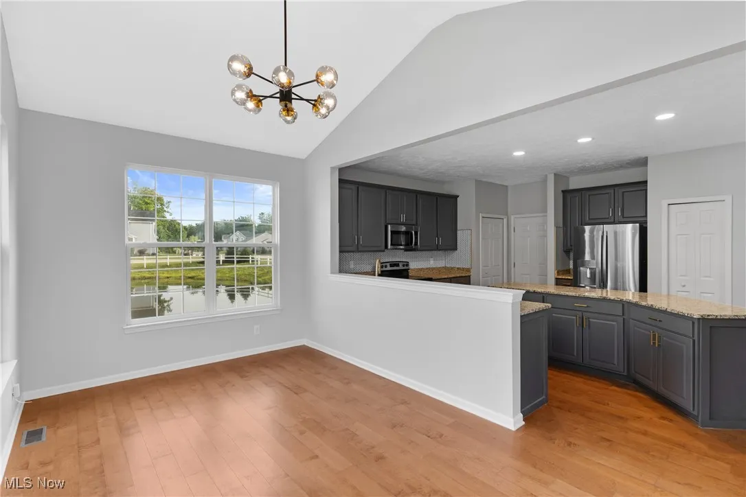 Kitchen with gray cabinetry, decorative backsplash, decorative light fixtures, a chandelier, and stainless steel appliances