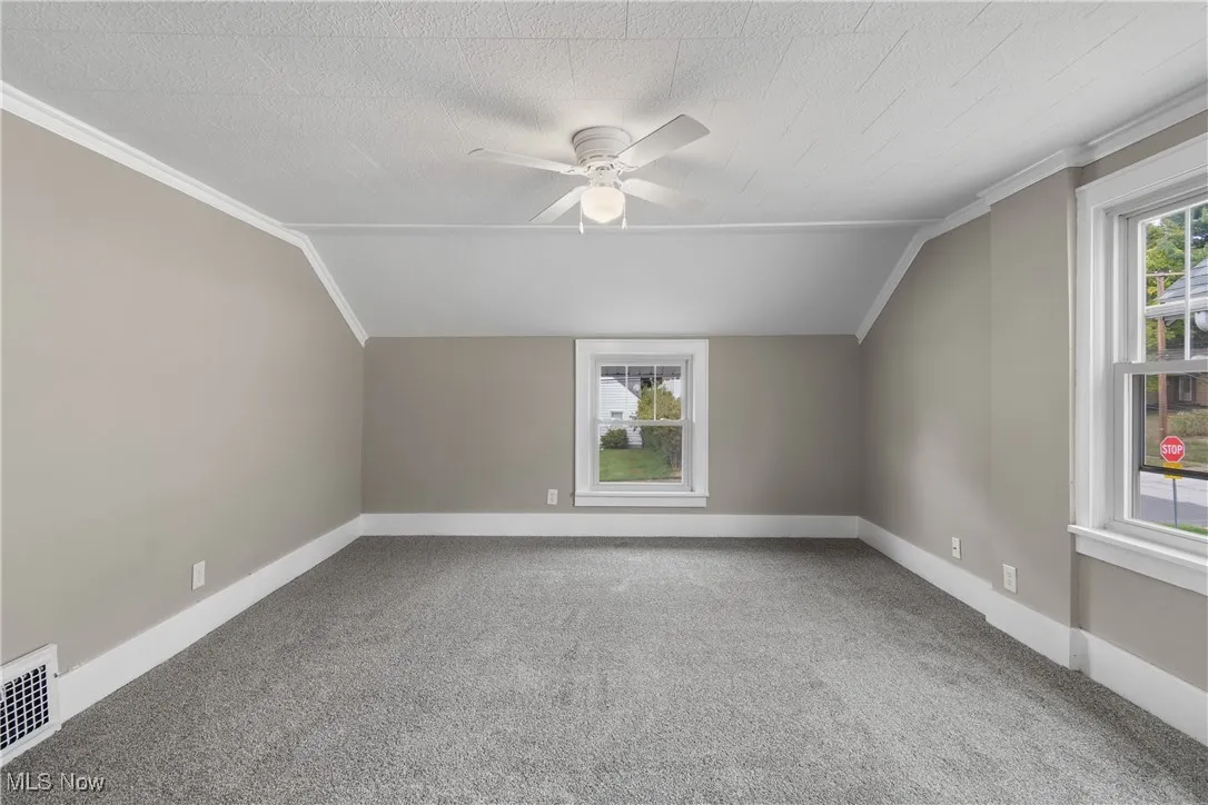 Bonus room featuring vaulted ceiling, light carpet, plenty of natural light, ceiling fan, and a textured ceiling