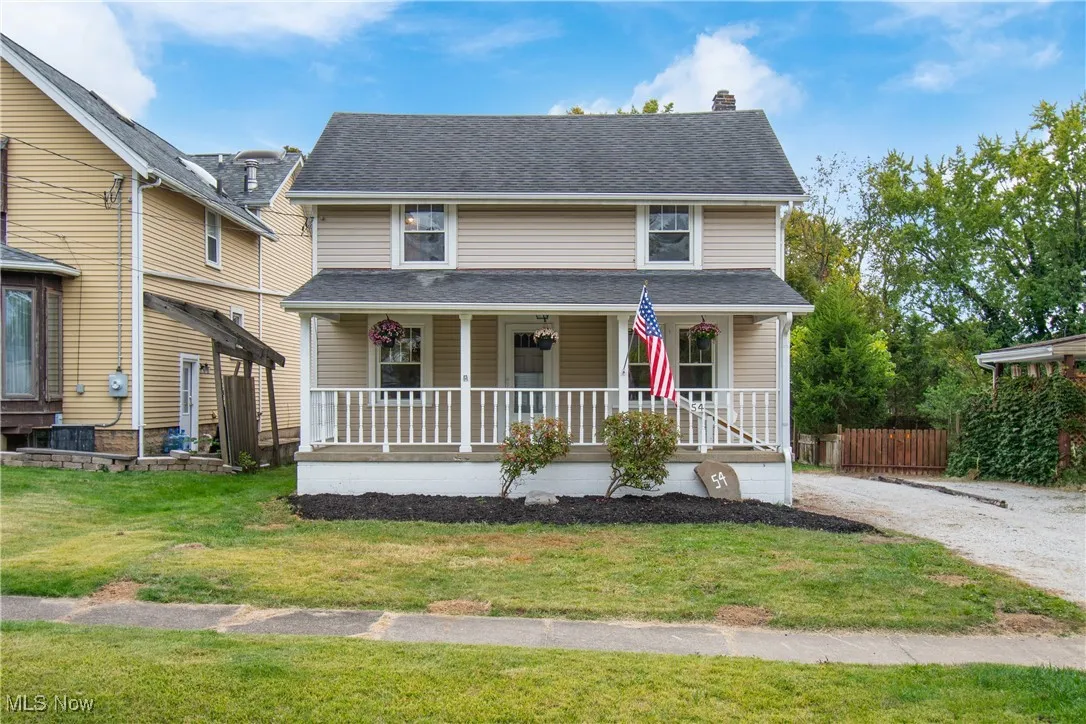 View of front of home with a porch, a front yard, a chimney, and roof with shingles