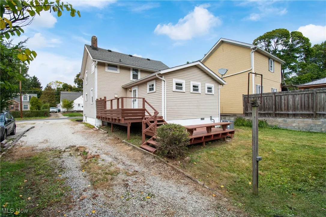 Back of house featuring a wooden deck and driveway