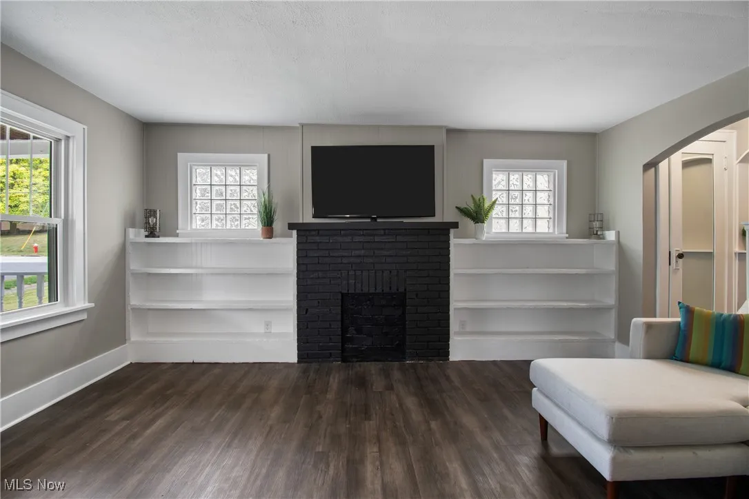 Living area featuring dark wood finished floors, arched walkways, and a fireplace