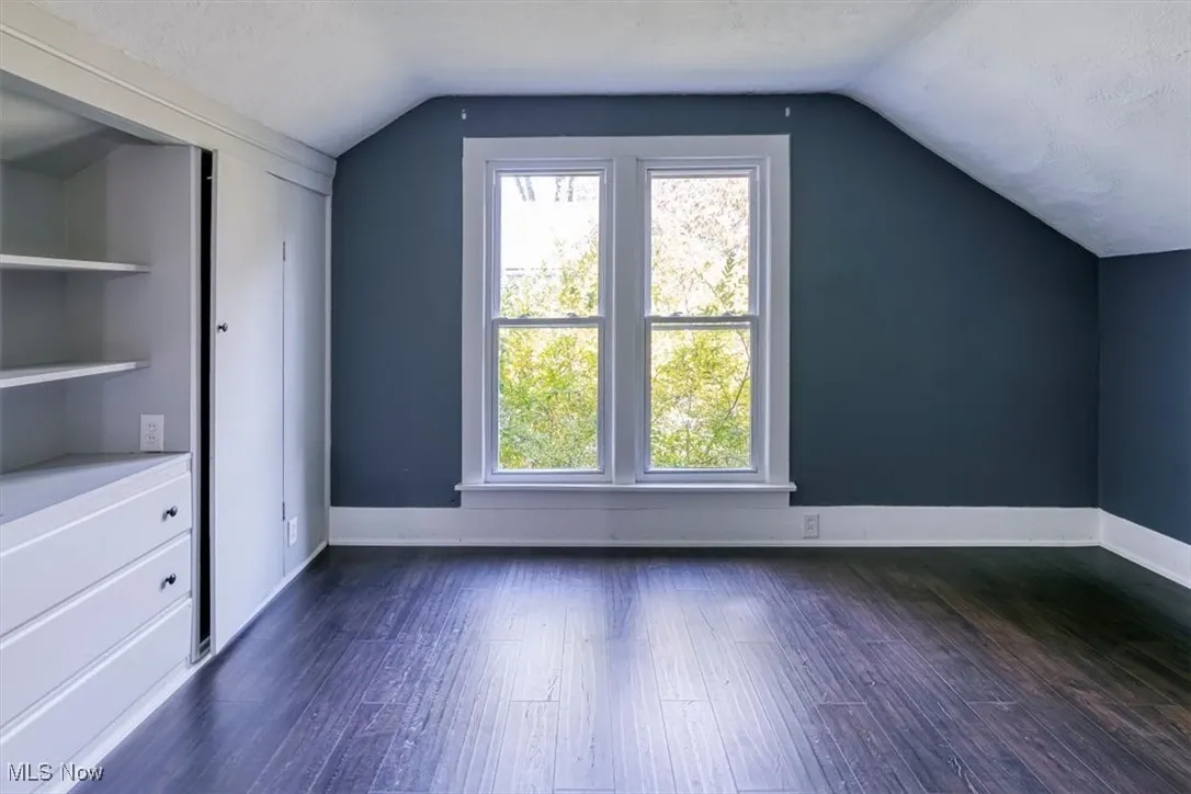 Additional living space featuring dark wood-type flooring, a textured ceiling, and lofted ceiling