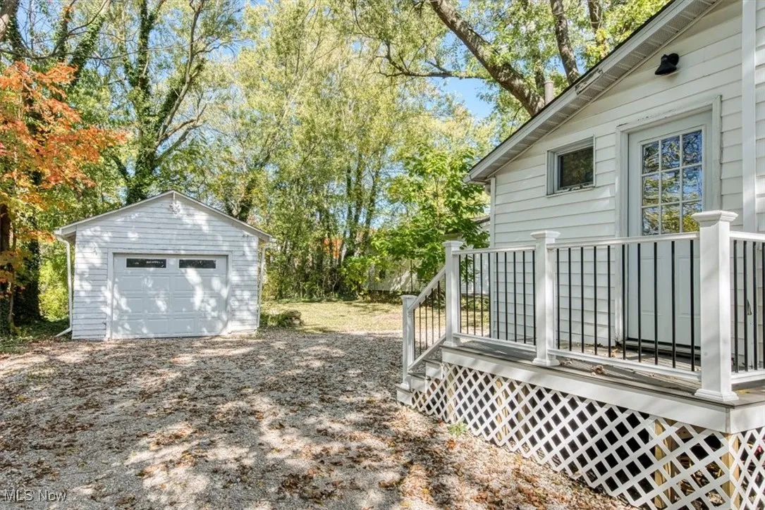 View of yard featuring an outbuilding, a wooden deck, a detached garage, and view of scattered trees