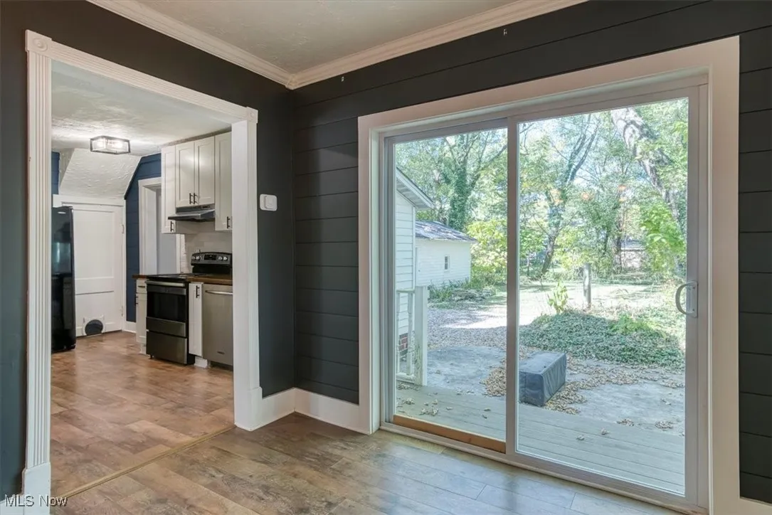 Doorway to outside featuring wood-type flooring and ornamental molding