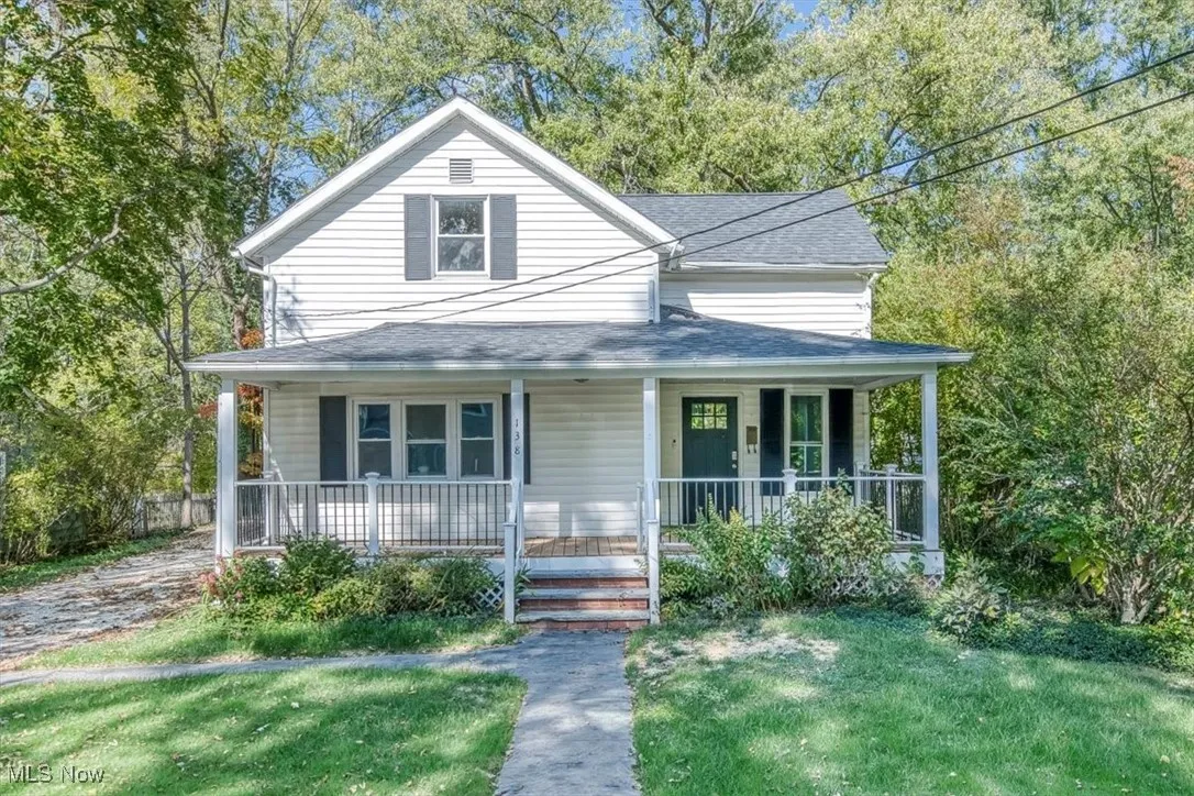 View of front of home featuring covered porch, a shingled roof, and a front lawn