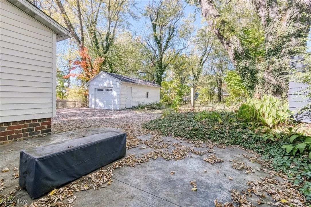 View of yard with a patio, an outdoor structure, a garage, and view of scattered trees
