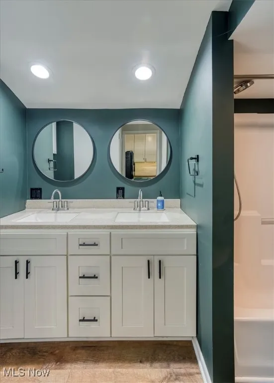 Full bath featuring double vanity, light wood-type flooring, recessed lighting, and shower / washtub combination