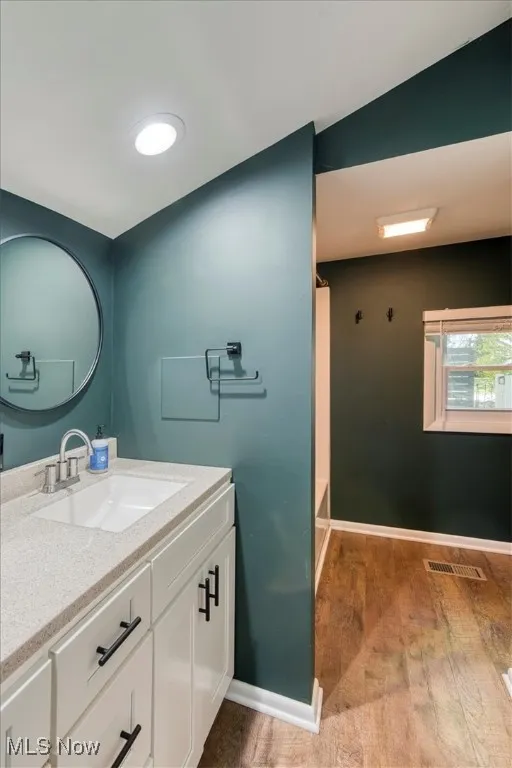 Bathroom with vanity, light wood finished floors, and shower / bathtub combination with curtain