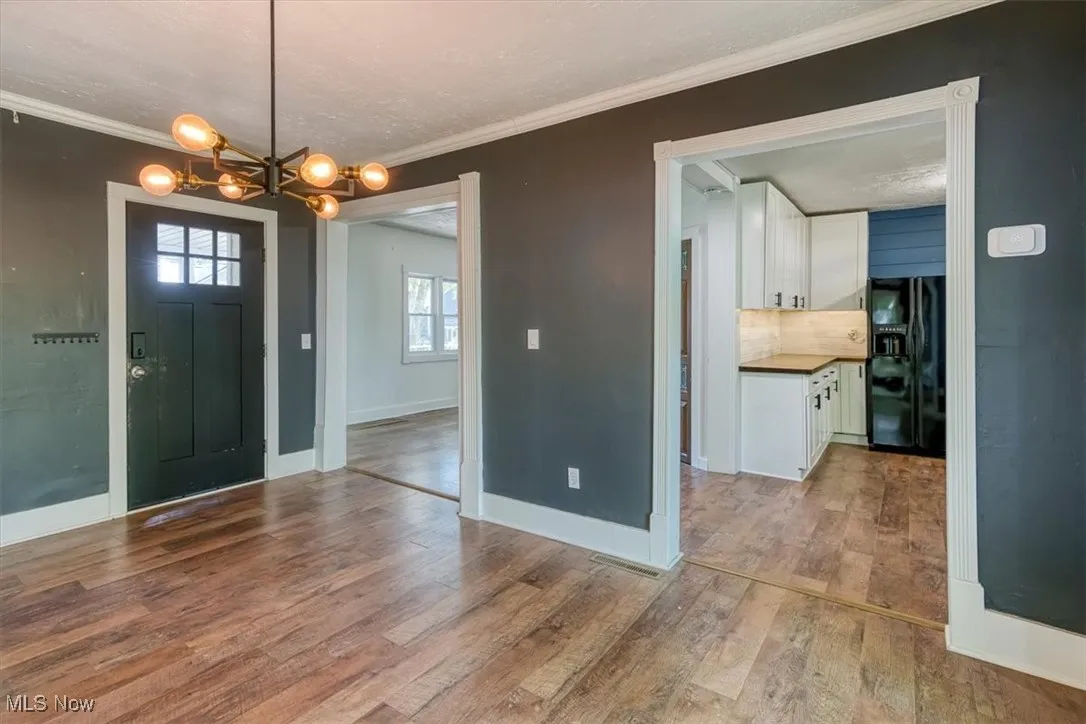 Entryway featuring crown molding, light wood-style flooring, a chandelier, and a textured ceiling