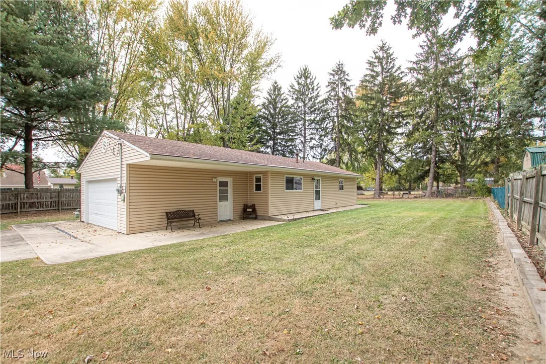 Rear view of house with a fenced backyard, a patio area, concrete driveway, a shingled roof, and an attached garage