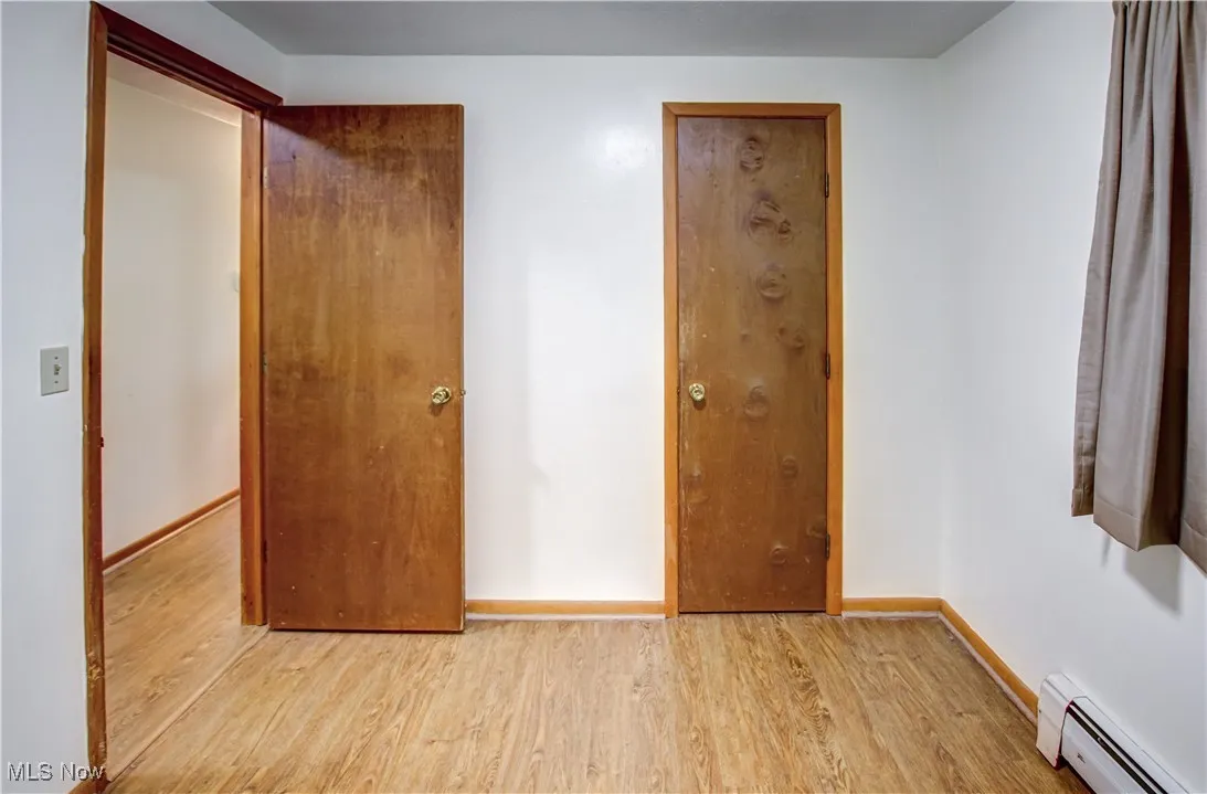 Bedroom featuring wood finished laminate floors and a baseboard heating