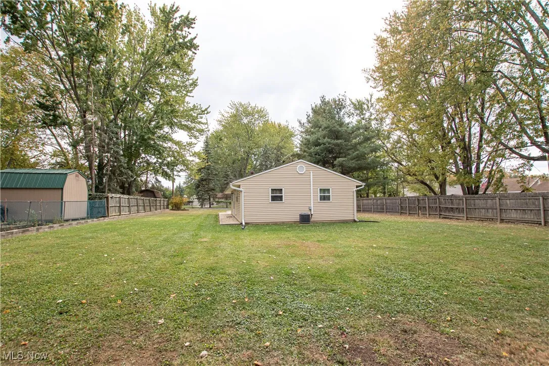 Fenced backyard showing side of home