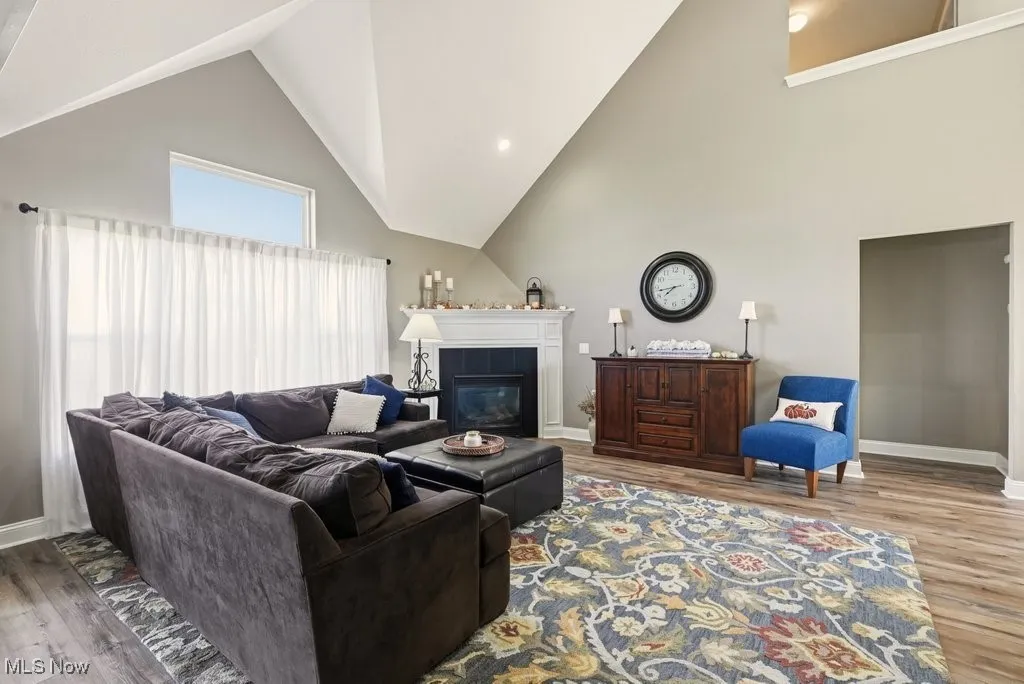 Living area with high vaulted ceiling, light wood-style floors, a fireplace, and recessed lighting