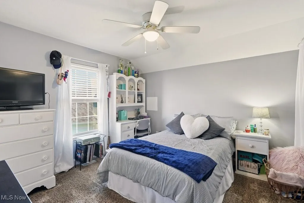 Bedroom featuring dark colored carpet, ceiling fan, and vaulted ceiling