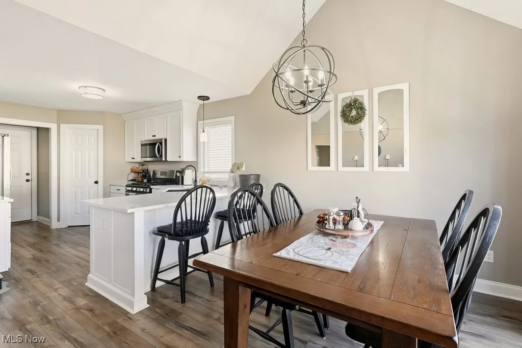 Dining space featuring light wood finished floors, a chandelier, and lofted ceiling