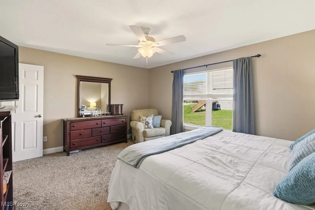 Carpeted bedroom featuring a ceiling fan and baseboards