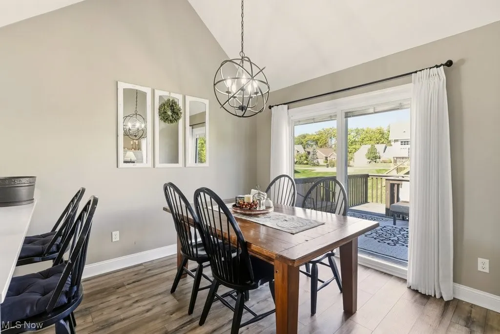 Dining area with a chandelier, wood finished floors, and high vaulted ceiling