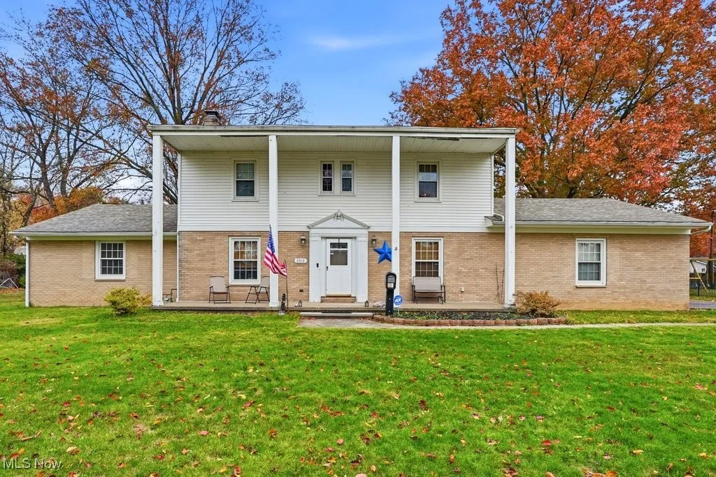 View of front of home featuring brick siding, a chimney, and a front yard