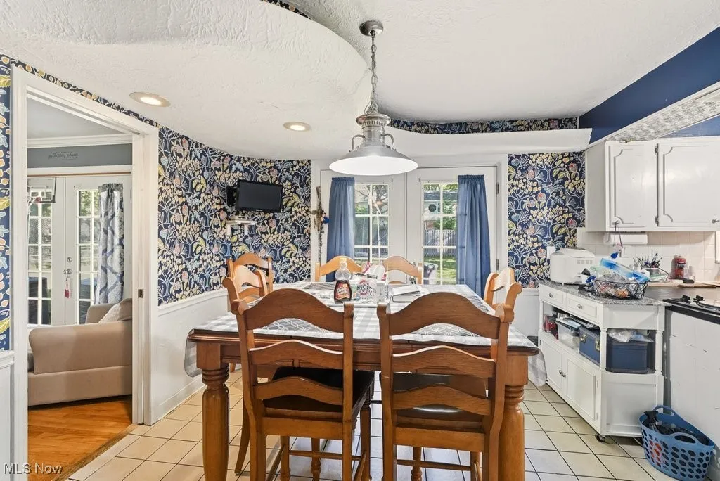 Dining room with wallpapered walls, french doors, light tile patterned flooring, a textured ceiling, and recessed lighting
