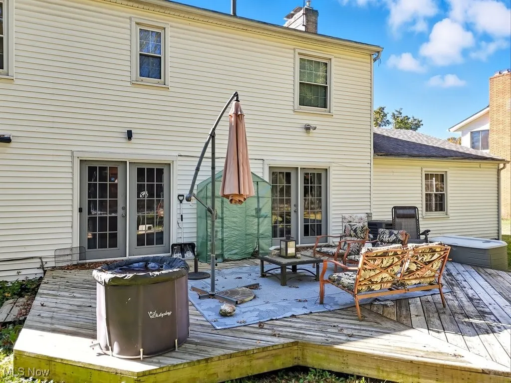 Back of house with a chimney, a deck, and an outdoor living space