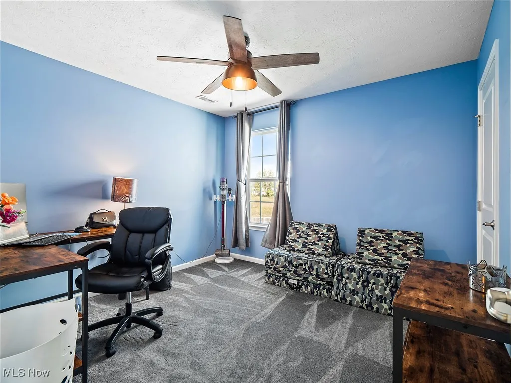 Office area featuring carpet, a textured ceiling, and a ceiling fan