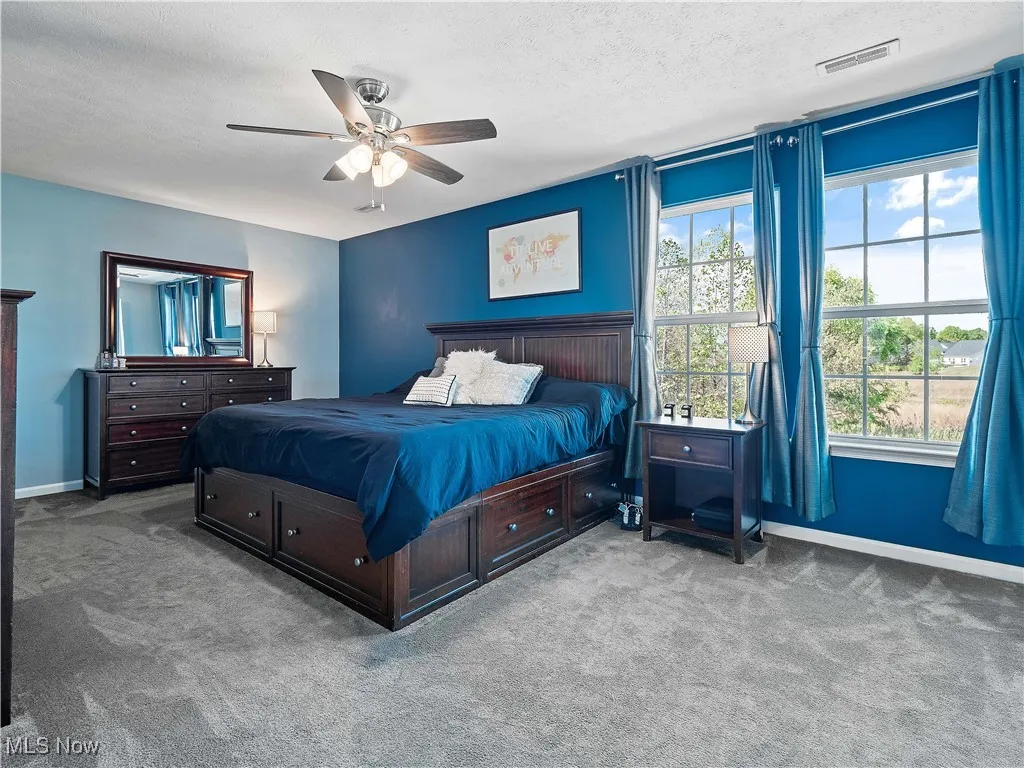Carpeted bedroom featuring a ceiling fan and a textured ceiling
