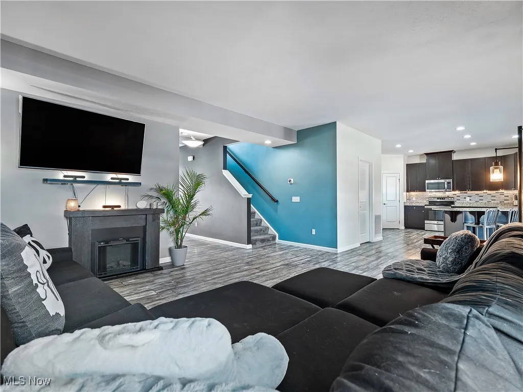 Living area featuring light wood finished floors, stairs, a fireplace, and recessed lighting