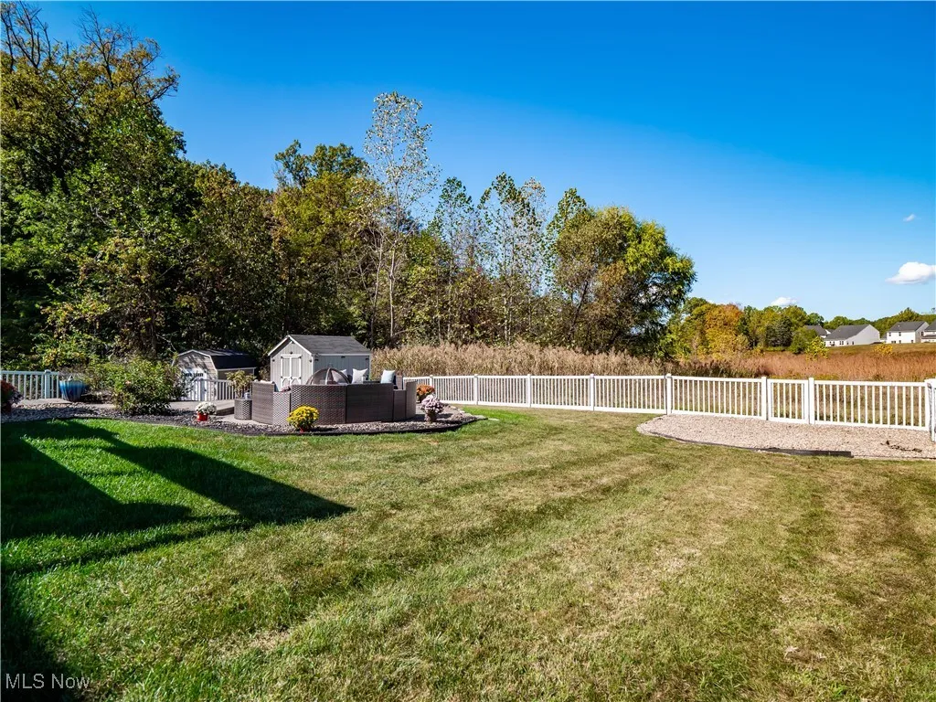 Fenced backyard featuring an outdoor hangout area and a storage unit