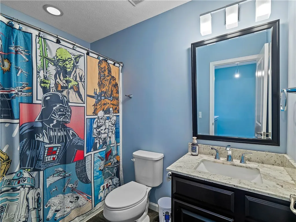Bathroom with vanity, curtained shower, and a textured ceiling