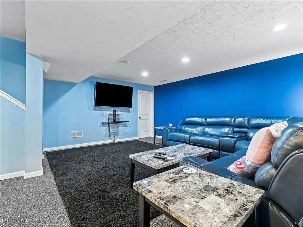 Living area with dark carpet, a textured ceiling, and recessed lighting