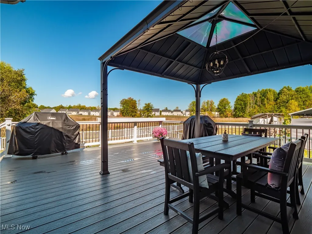 Wooden deck with area for grilling, outdoor dining area, and a gazebo