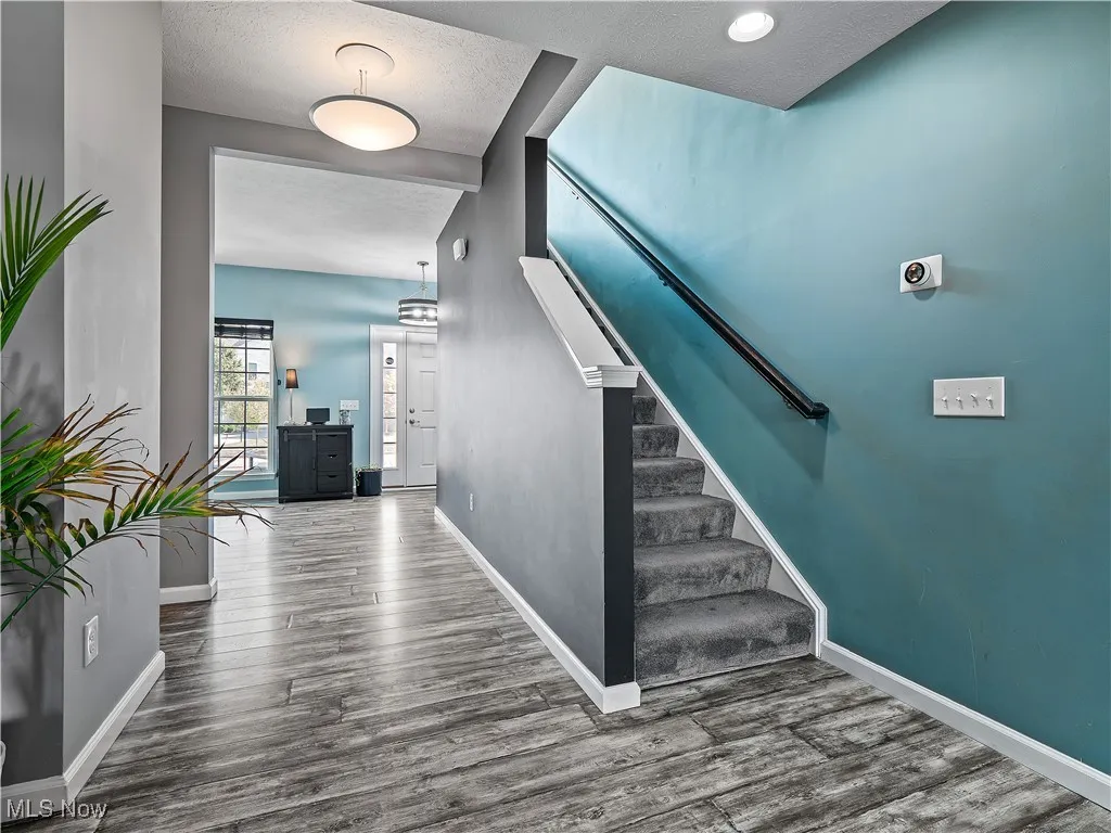 Staircase featuring a textured ceiling and wood finished floors