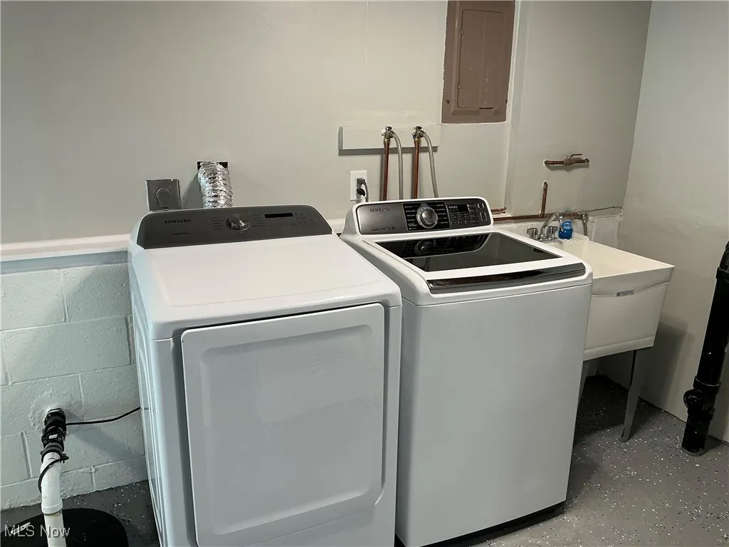 Laundry featuring electric panel and washing machine and clothes dryer