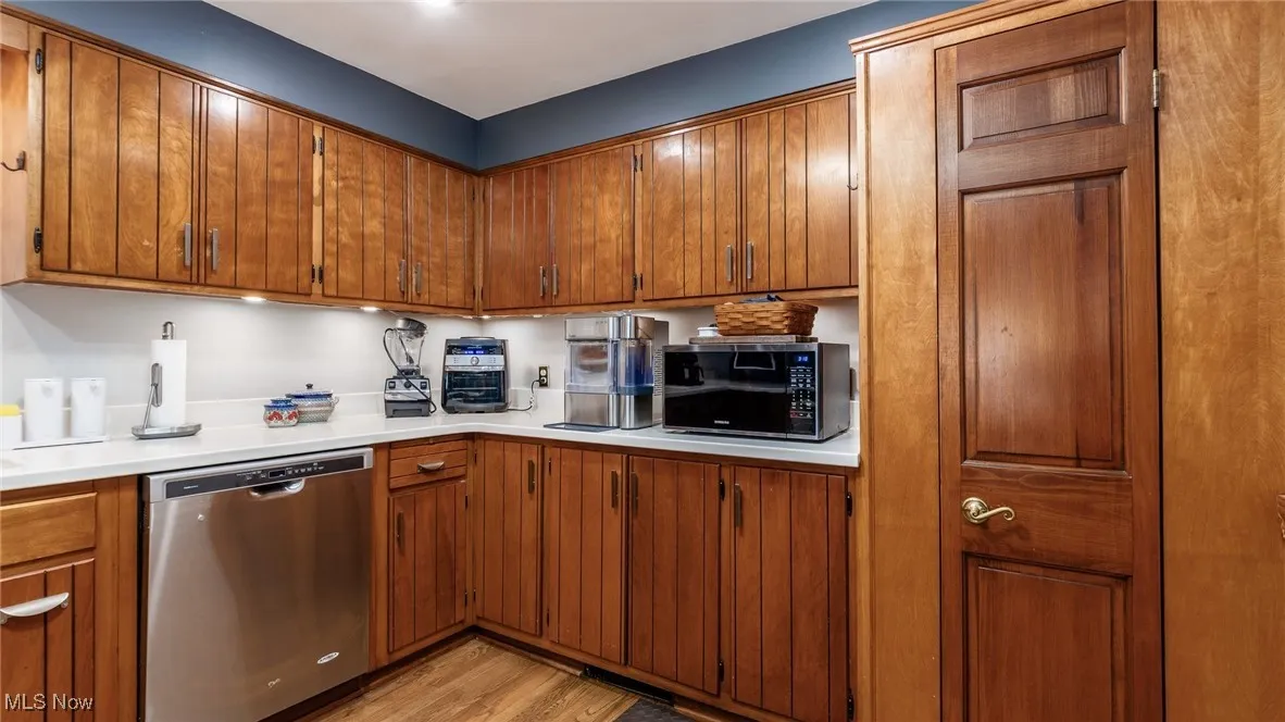 Kitchen with dishwasher, black microwave, light countertops, and light wood-style flooring