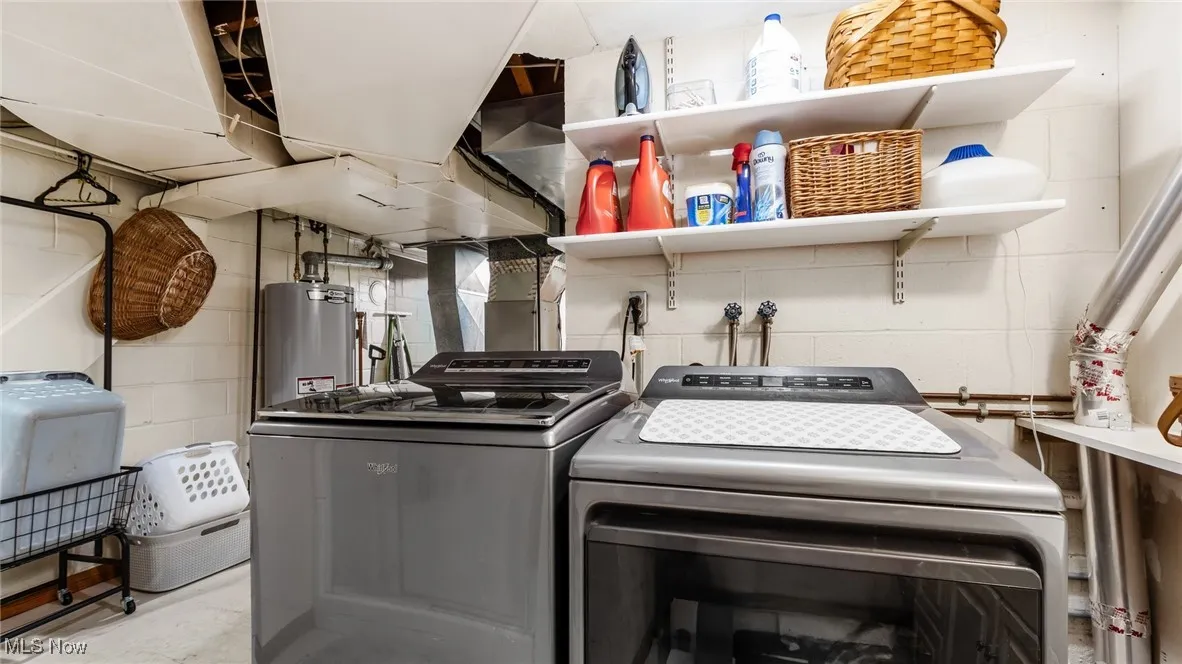 Washroom featuring water heater and washing machine and clothes dryer