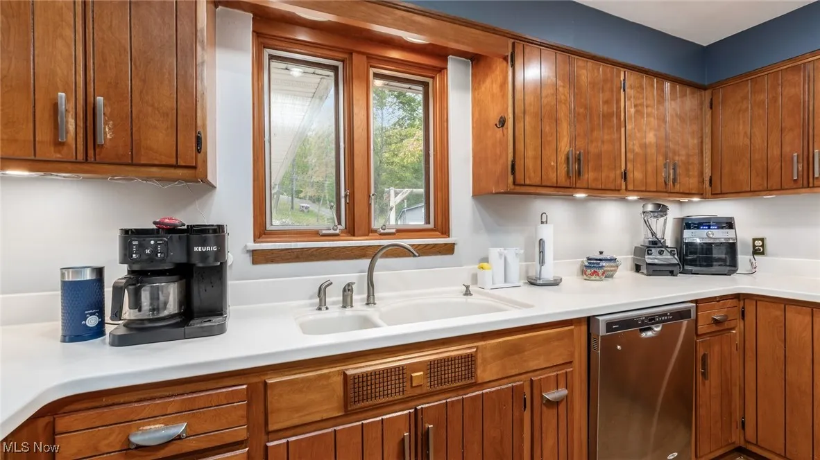 Kitchen with dishwasher, light countertops, and brown cabinetry