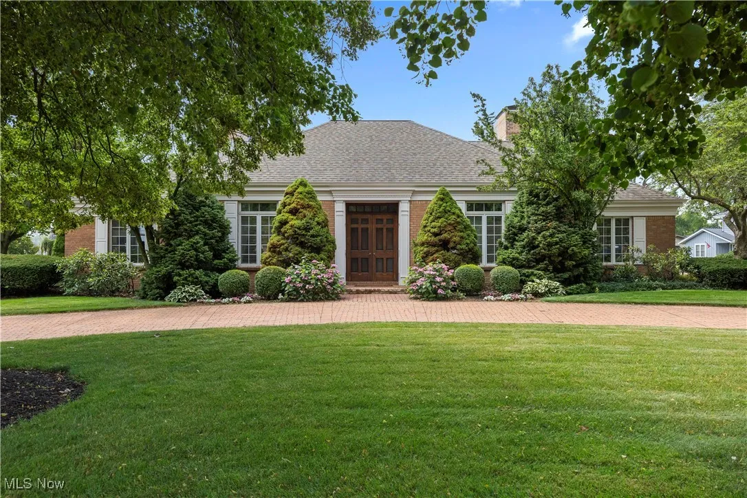View of front of home featuring a front yard, brick siding, a chimney, and a shingled roof