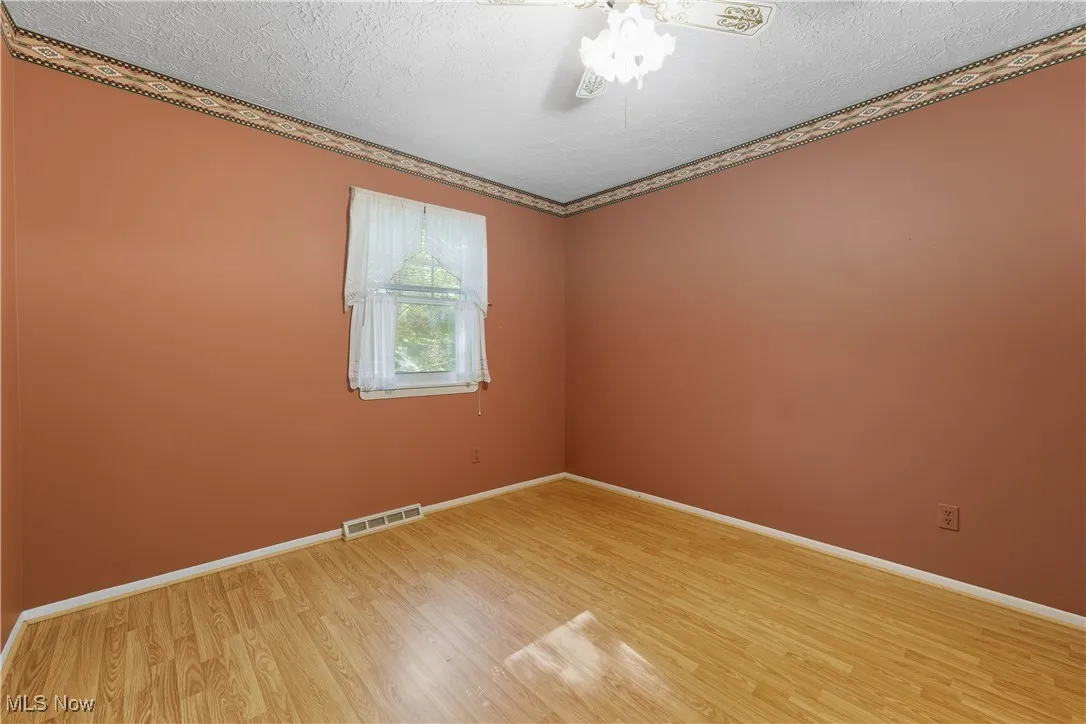 Unfurnished room with light wood-type flooring, a textured ceiling, and crown molding