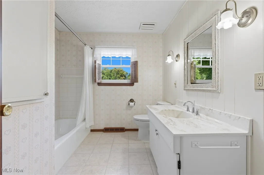 Full bathroom with shower / bath combination with curtain, light tile patterned floors, a textured ceiling, and vanity