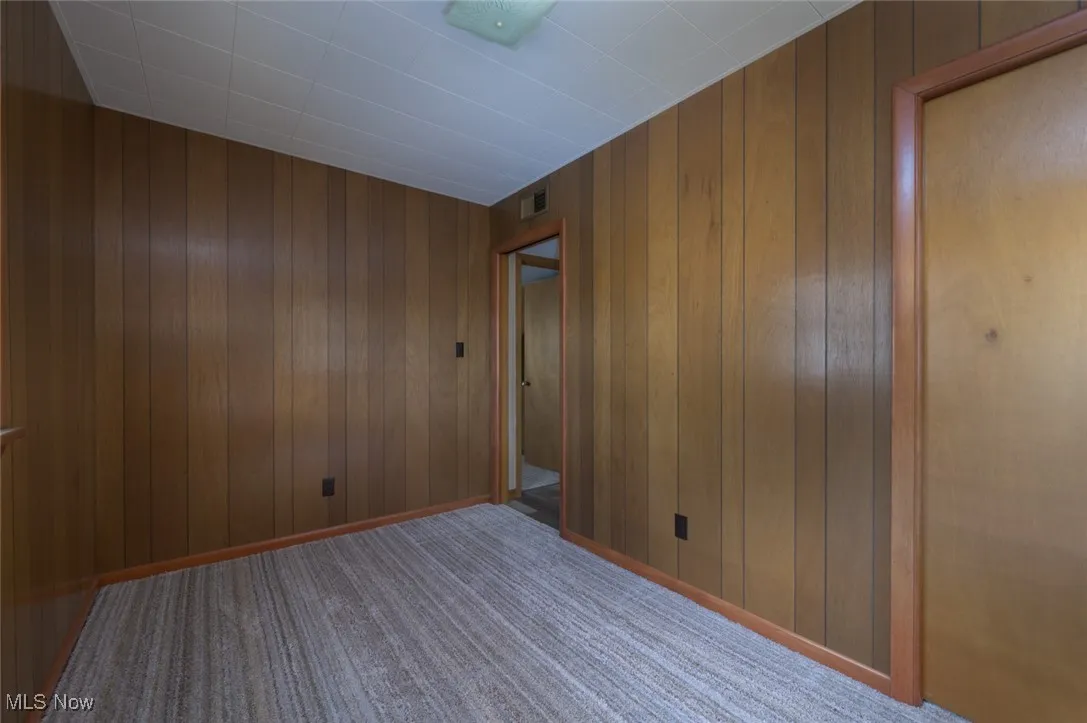 Unfurnished room featuring carpet flooring and wooden walls