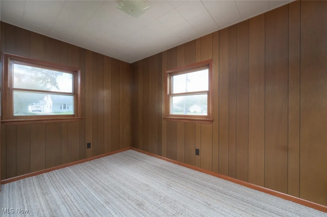 Empty room featuring wooden walls and light colored carpet
