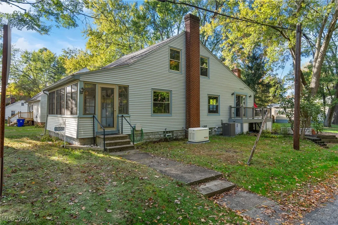 View of home's exterior with a chimney, a sunroom, and a lawn